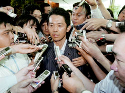 Agriculture Minister Norihiko Akagi is surrounded by reporters Wednesday after he tendered his resignation to Shinzo Abe at the Prime Minister's Official Residence