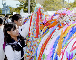 High school students hang strings of paper cranes in Nagasaki's Peace Park to pray for peace on the 62nd anniversary of the atomic bombing of the city