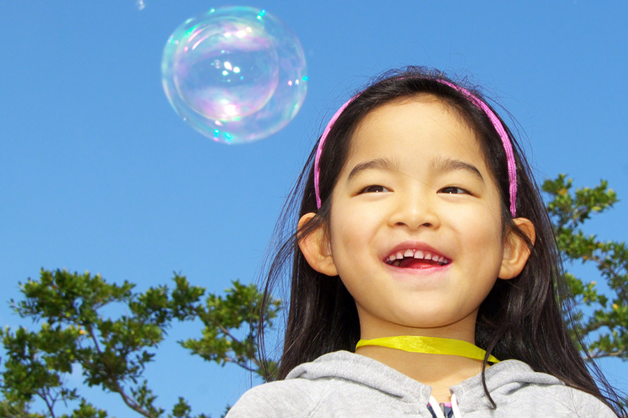 A happy child at the bubble-blowing machine, Okinawa Pref.